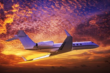 Private jet cruising in a sunset sky