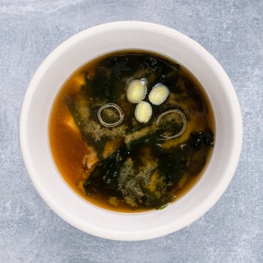 Japon miso çorbası. Masada tofu var. Gri arka planda seramik kasede. Soya soslu miso çorbası.
