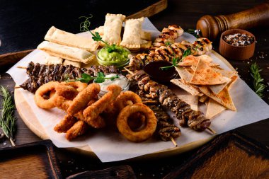 Tavuk kebabı, şiş kebap ve abur cubur soğan halkaları ve ahşap tabakta atıştırmalıklar.