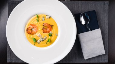 Karidesli sarı kremalı çorba. Sonbahar yemeği balkabağı çorbası ve karides. Akşam yemeği için sunulan üst görünüm, düz yatış