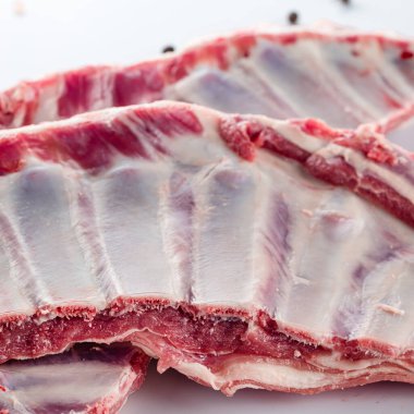 Beyaz arka planda pişmemiş baharatlarla çiğ sığır kaburgalarını kapatın.