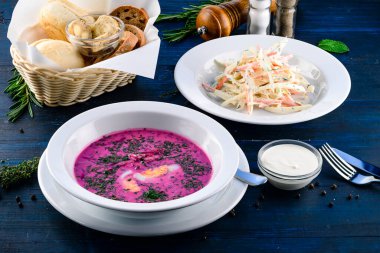 İki tabak çorba ve salata, iki çeşit yemek, ahşap bir masada servis edilmiş.