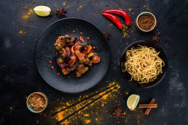 Ekşi soslu tavuk. Teriyaki tavuğu siyah taş zemin üzerinde Çin tavuğu tatlı ve ekşi sos, erişteyle servis edilir.