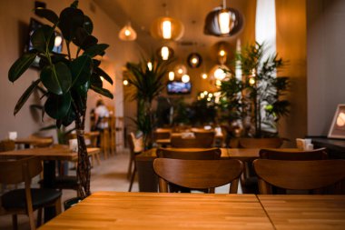 Ahşap masaları ve sandalyeleri olan güzel bir restoran. Lokanta kafesinin iç kısmı, yakın plan, yumuşak odaklı. Sığ DOF
