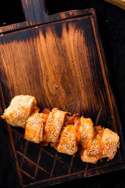 Tahta bir tahtanın üzerinde puf böreğinden yapılmış pizza calzone, tahta bir masanın üstünde katlanmış pizza Calzone, fotokopi alanı arka planında düz bir şekilde yatıyordu.