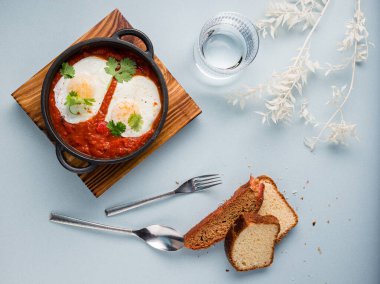 Dökme demir bir tavada yumurta, domates ve maydanozlu Shakshuka, geleneksel İsrail karıştırılmış Arapça domatesli yumurta.