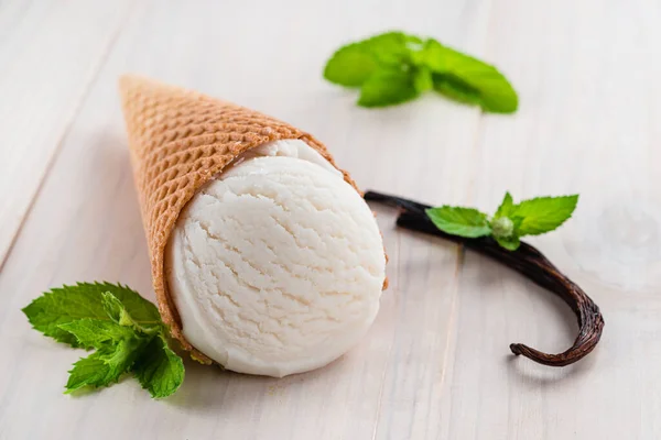 White ice cream with vanilla pod and mint in a cone on a white background — Stock Photo, Image