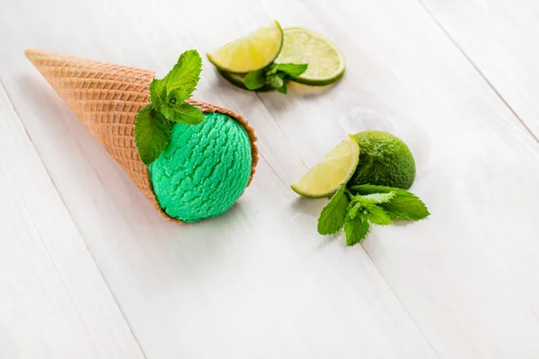 Zelená zmrzlina s vápnem a mátou v kuželu na bílém pozadí — Stock fotografie