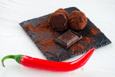 Ahşap arka planda kırmızı biberli çikolata parçaları. Kırık siyah çikolata
