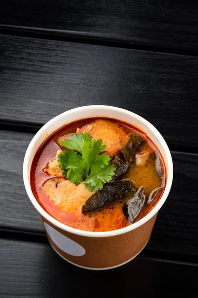 tom yam soup in a paper bowl to take away, traditional Thai tom yam soup. Delivery concept. Eco packages concept