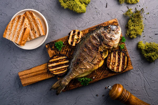 grilled sea bream on wooden board, grilled dorado is served with vegetables