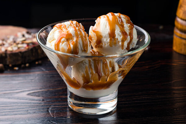 ice cream balls with caramel, Tasty ice cream with caramel sauce in bowl on wooden board