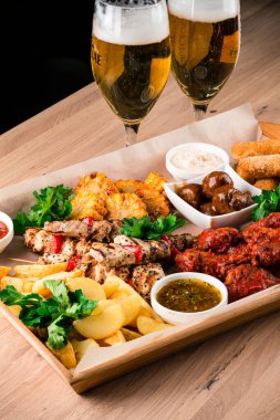 Büyük bir bira tabağı, büyük bir paket abur cubur. Karışık abur cuburlar, bol yağda kızartılmış bira. Büyük bir şirket için tatil için yiyecek. Bira için sıcak et atıştırmalıkları ahşap tabakta servis edilir.