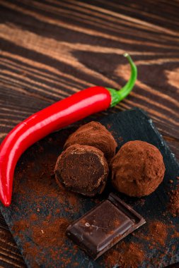 Biberli çikolata şekeri. Ahşap arka planda kırmızı biberli çikolata parçaları. Kırık siyah çikolata