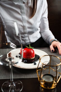 Güzel bir kadının bir restoranda oturmuş kokteyl içerken kırmızı tatlı yediği yakın plan.