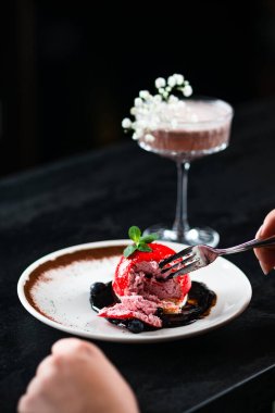 Güzel bir kadının bir restoranda oturmuş kırmızı tatlı yediği kırmızı kadife pastayı.