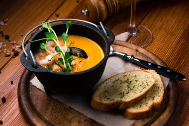 Deniz mahsullü bouillabaisse çorbası. Fransız balık çorbası Bouillabaisse kızarmış baget deniz ürünleri kremalı çorba ve siyah tabakta karides..
