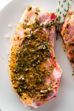 Terbiye edilmemiş domuz pirzolası. Pişirmek için marine edilmiş domuz eti, barbekü için et, sarımsak ve otlar marine edilmeye hazır. Organik çiğ domuz eti.
