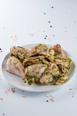 Çiğ salamura edilmiş tavuk kanatları ve baharatlar. Üst manzara, soslu marine edilmiş çiğ tavuk pesto soslu. Soslu ve baharatlı taze tavuk budu.