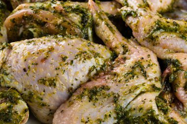 Çiğ salamura edilmiş tavuk kanatları ve baharatlar. Üst manzara, soslu marine edilmiş çiğ tavuk pesto soslu. Soslu ve baharatlı taze tavuk budu.