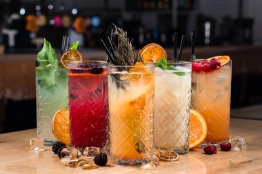 Bar tezgahında beş renkli cin tonik kokteyli, tezgahta beş limonata.