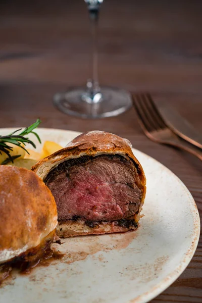 Perfect homemade juicy Beef Wellington, tenderloin dish on wooden table, Full beef wellington portion with potatoes close up. Traditional British Food
