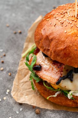 Pastırmalı hamburger, et, ahşap arka planda. Roka soslu pastırmalı burger, büyük boy sandviç.