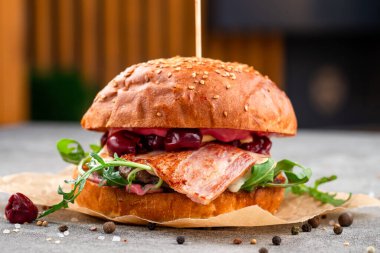 Pastırma ve kiraz burger, kızarmış pastırma ve kiraz dilimli yaratıcı hamburgerler, taze roka. Sokak yemekleri konsepti.