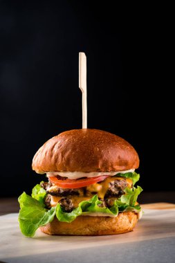 Pirzola, peynir ve salatalı duble burger. Duble sığır pirzolası, peynir ve sebze salatası..