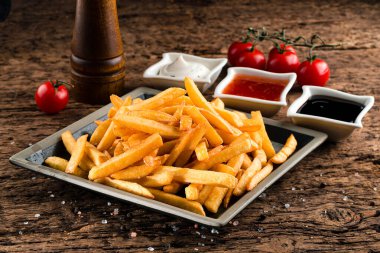 Patates kızartması, patates kızartması ve ketçap. Sağlıksız yemek geçmişi, ahşap arka plana yakın çekim.