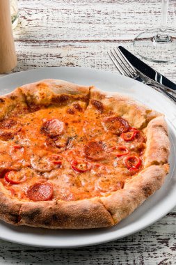 Lezzetli klasik İtalyan pizzası Pepperoni, ahşap bir masada dilimlenmiş salam pizzası.