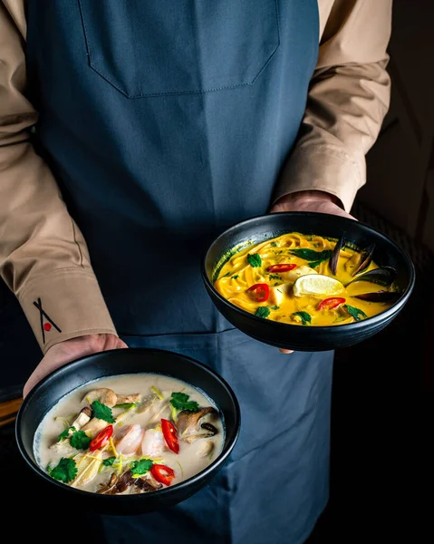 two Asian Vietnamese soups in the hands of a waiter. Hands of Thai Chef with delicious soup with noodles and pork of restaurant traditional Thai food.