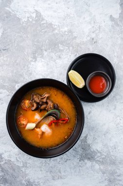 Klasik Tom Yam Tayland yemeği. Geleneksel baharatlı Tayland çorbası Tom Yum karides ve deniz ürünleri ile taş zeminde seramik kasede