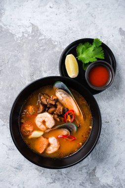 Klasik Tom Yam Tayland yemeği. Geleneksel baharatlı Tayland çorbası Tom Yum karides ve deniz ürünleri ile taş zeminde seramik kasede