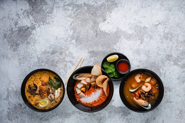 set of traditional thai soup tom yam and tom kha with seafood, chicken, coconut milk and hot spices. Top view with copy space