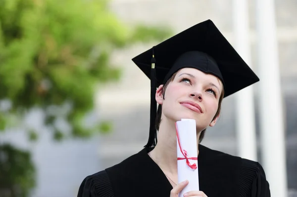 Hübsche Yang-Studentin, die gerade ihren Abschluss gemacht hat und in den Himmel blickt. — Stockfoto