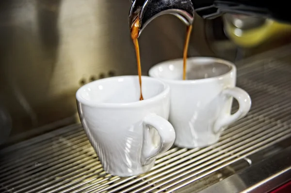 İki fincan kahve kahve makinesi önünde.