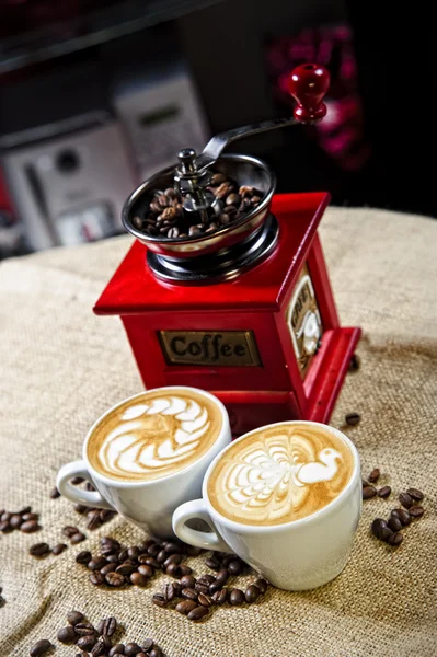 Picture of coffee cups in front of manual coffee grinder — Stock Photo, Image