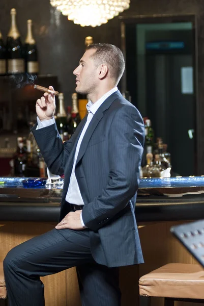 Businessman smoking cigar next to bar stand