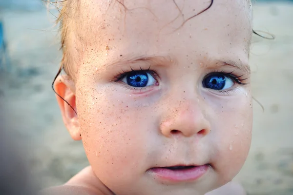 Pieni hauska poika sinisilmäinen leikkii rannalla — kuvapankkivalokuva