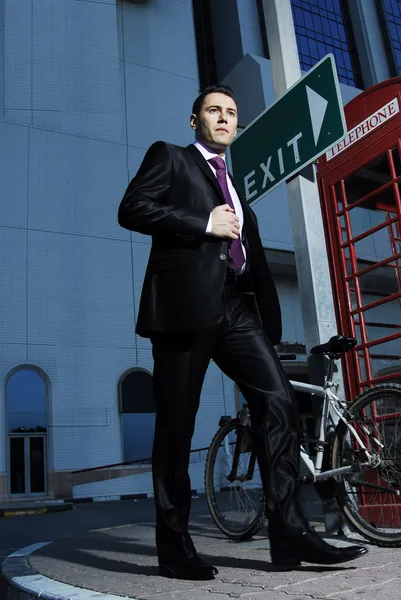 Successful yang man in business suit posing in front of vintage phone booth — Stock Photo, Image