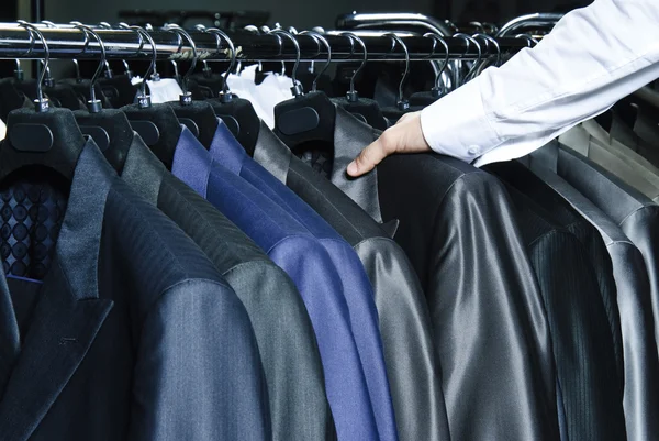 Mężczyzna wybierając kurtkę biznesową z surowego w sklepie — Zdjęcie stockowe