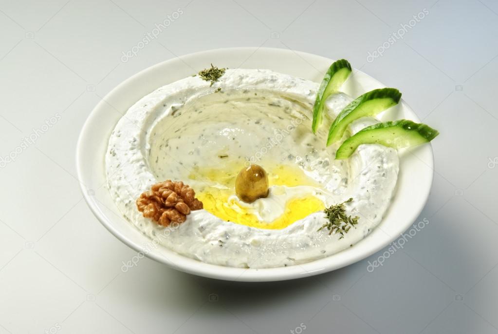 Plate of traditional Arabic hummus,arranged topped with fresh cucumbers and nuts