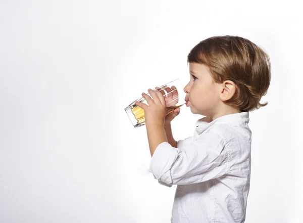 Kleiner netter Junge mit einem Glas Apfelsaft auf weißem Hintergrund — Stockfoto