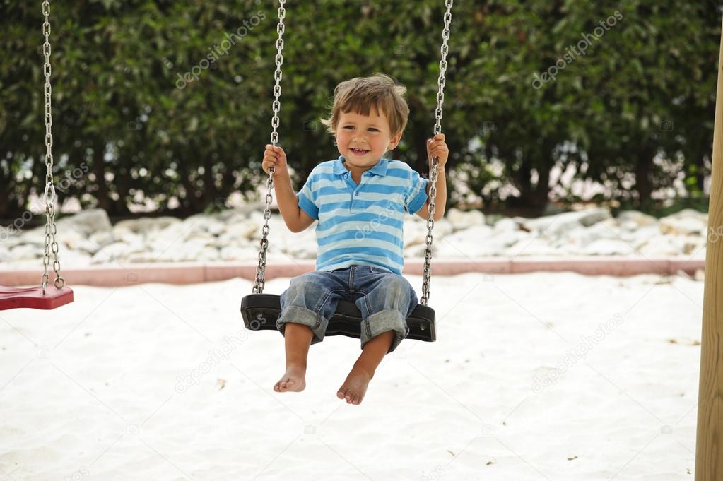 Little cute boy having fun on chain swings