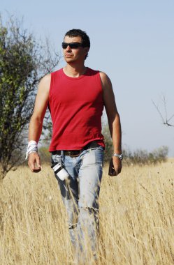 Yang ve kendine güvenen adam yürür uzun kuru otların arasında