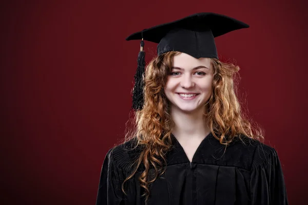 カップとガウンを着て美しい巻き毛女子大学卒業生のスタジオ ポートレート — ストック写真