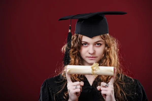 컵과 가운에서 옷을 입고 아름 다운 곱슬 졸업 학생의 스튜디오 초상화 — 스톡 사진