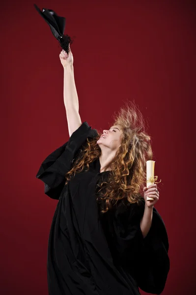 Portrait studio de belle étudiante diplômée bouclée vêtue d'une tasse et d'une robe — Photo