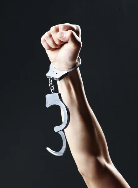 Фото наручников, висящих на протянутой руке — стоковое фото